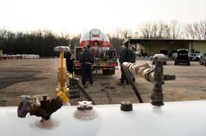 Tank being pumped out in the foreground with the pumping bobtail truck in background.