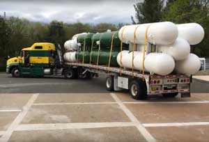 Semi truck dropping off horizontal tanks.